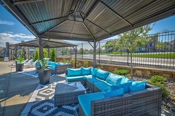 a lounge area with blue couches and tables under a roof